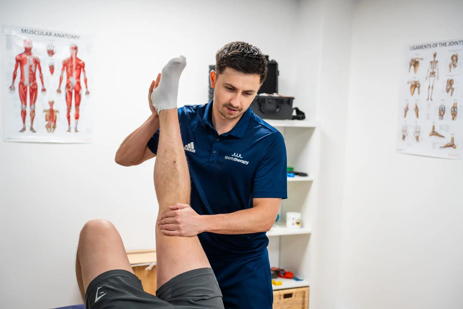 Jonny, owner and clinical lead at JWL Sports Therapy, assessing a patient's leg in JWL's treatment room